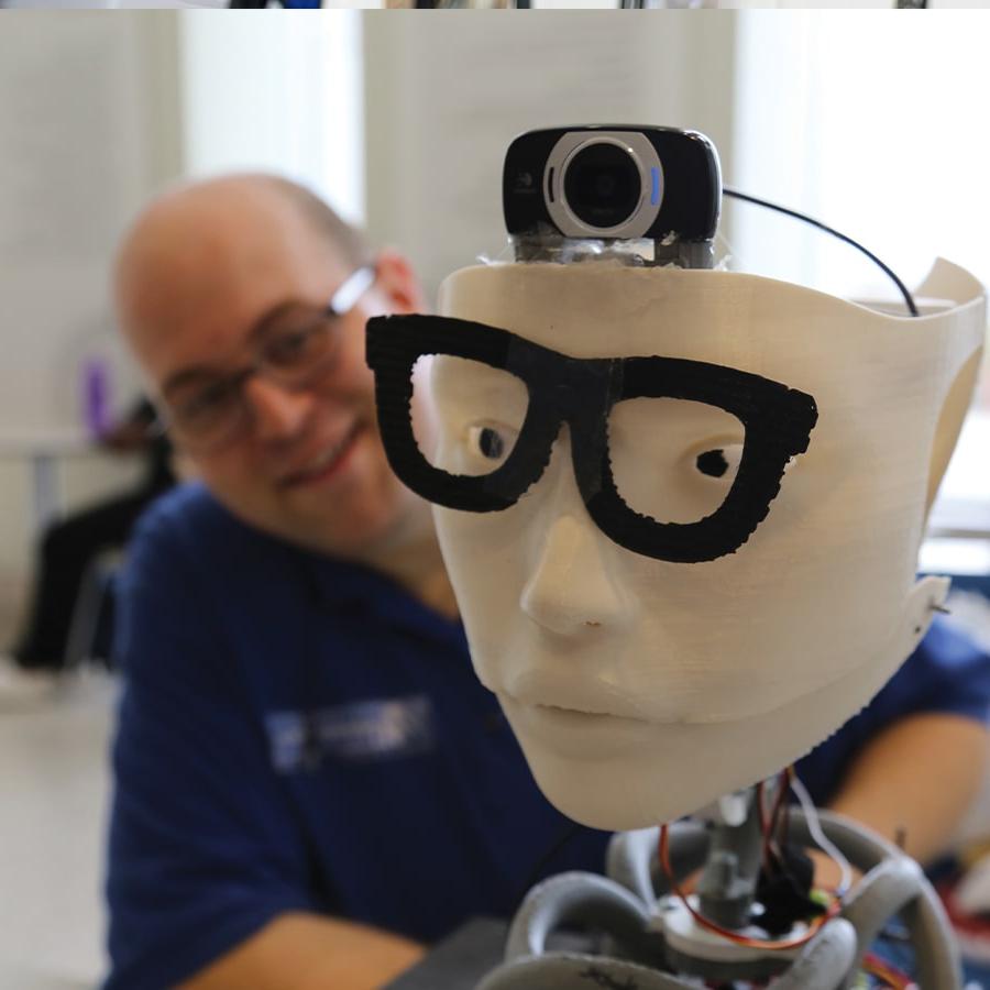 Photo of John Mazzarella with a robot head photo by Lisa Link.
